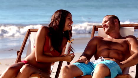 Cheerful-woman-applying-sunscreen-to-her-boyfriend
