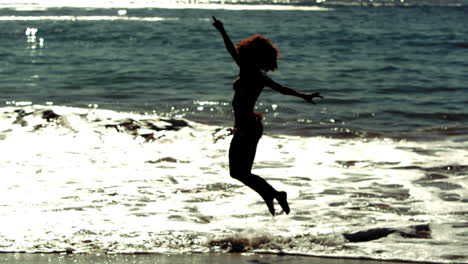 Woman-jumping-and-raising-arms-and-legs-in-the-sea
