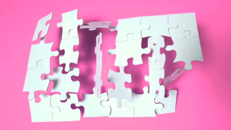 Jigsaw-puzzle-falling-on-pink-surface