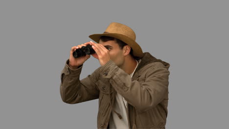 Man-wearing-a-coat-using-binoculars-on-grey-screen