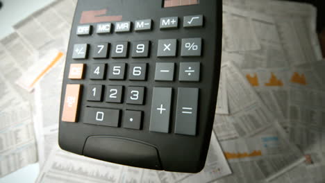 Schwarzer-Taschenrechner-Fällt-Und-Springt-Auf-Papier