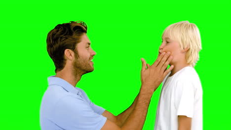 Man-pressing-inflated-cheeks-of-his-son-on-green-screen