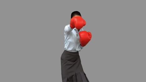 Businesswoman-with-boxing-gloves-hitting-on-grey-screen