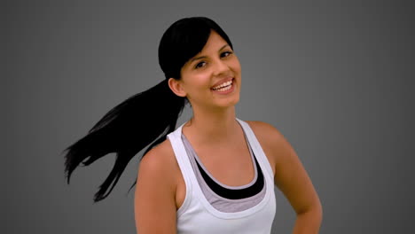 Fit-brunette-smiling-at-the-camera-and-tossing-hair