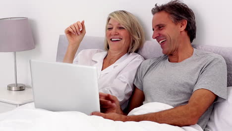 Mature-couple-using-laptop-in-the-bed