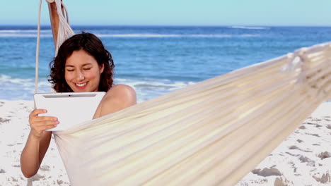 Mujer-Sonriente-Usando-Tableta-En-Una-Hamaca