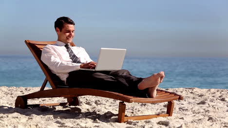 Unstressed-businessman-using-laptop-on-the-beach