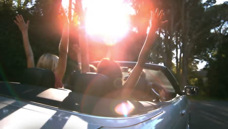 Friends-raising-their-hands-in-the-air-while-man-is-driving