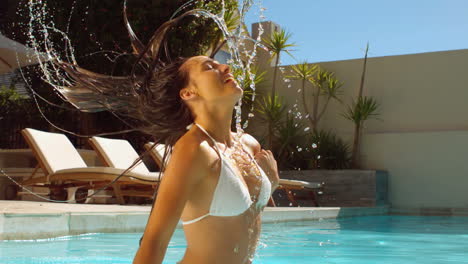 Woman-in-swimming-pool-tossing-her-wet-hair-