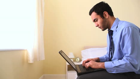 Portrait-of-a-businessman-using-his-laptop-in-bed