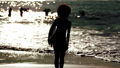 Silueta-De-Una-Mujer-Sosteniendo-Una-Tabla-De-Surf-En-La-Playa