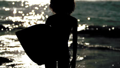 Silhouette-of-an-attractive-woman-holding-her-surfboard