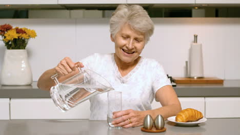 Mujer-Jubilada-Vertiendo-Un-Vaso-De-Agua-Para-El-Desayuno.