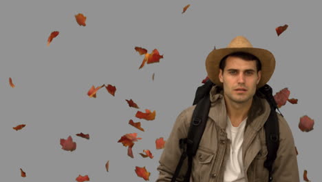 Man-with-a-hat-walking-under-leaves-falling-on-grey-screen