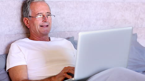 Elderly-man-using-laptop-in-bed