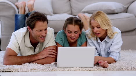 Parents-and-daughter-using-laptop-on-floor