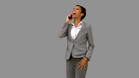 Businesswoman-laughing-while-phoning-on-grey-screen