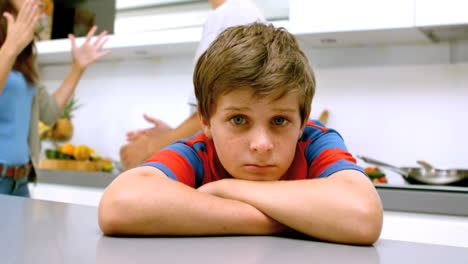 Sad-boy-with-arms-folded-while-parents-quarreling