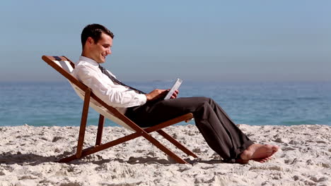 Hombre-De-Negocios-Sonriente-Usando-Tableta-Y-Relajándose-En-La-Playa