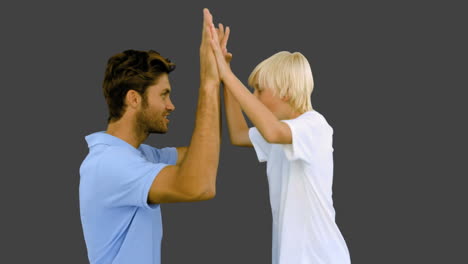 Man-giving-high-five-to-his-son-on-grey-background