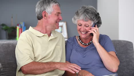 Pareja-Madura-Teniendo-Una-Conversación-Telefónica-Mientras-Lee-Un-Libro