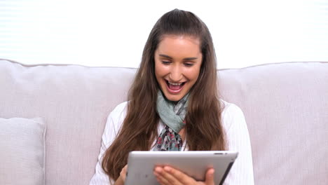 Smiling-brunette-using-tablet-pc-on-sofa-