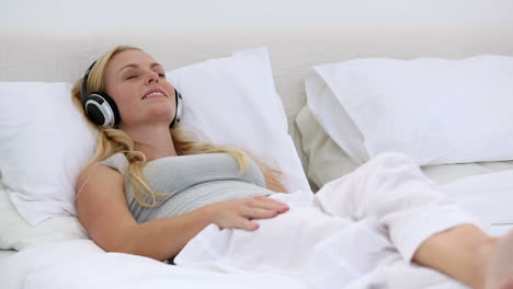 Blonde-woman-enjoying-listening-to-music-on-bed