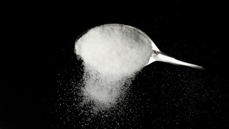 Spoon-pouring-sugar-powder-on-black-surface