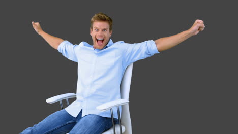 Man-on-swivel-chair-raising-arms-to-show-his-success-on-grey-screen