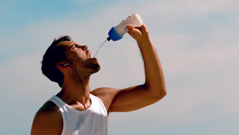 Athletic-man-rehydrating-with-water-on-the-beach