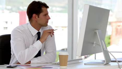 Businessman-examining-documents-helped-by-his-computer