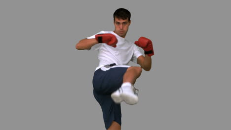 Boxer-performing-a-high-kick-on-grey-screen-