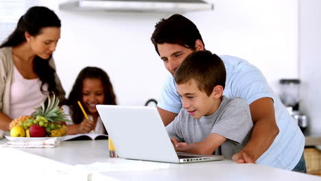 Padre-Mirando-La-Computadora-Portátil-Con-Su-Hijo-Y-La-Madre-Entra-Para-Ayudar-A-Su-Hija