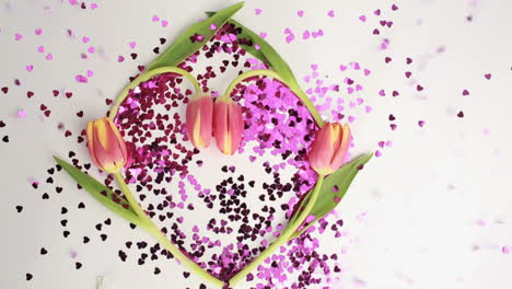 Heart-made-of-pink-confetti-framed-by-tulips-dispersing