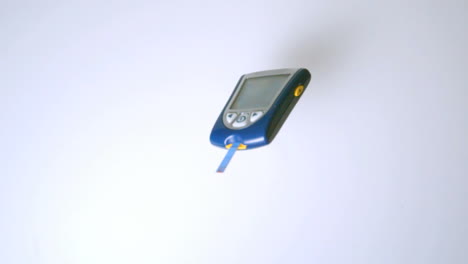Blood-glucose-monitor-falling-on-white-surface