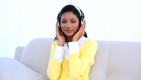 Woman-wearing-headphones-for-listening-music-on-sofa-