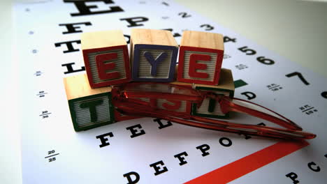 Eine-Brille-Fällt-Neben-Blöcke,-Die-Einen-Sehtest-Buchstabieren