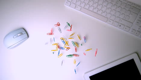 Colourful-paperclips-falling-on-office-desk