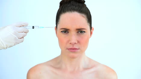 Hand-putting-a-syringe-on-the-forehead-of-a-troubled-woman-