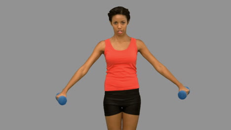 Pretty-woman-lifting-dumbbells-on-grey-screen