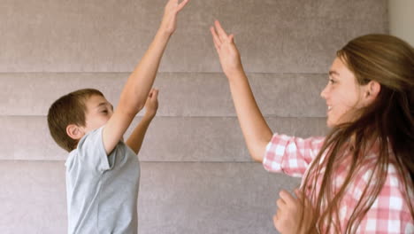 Siblings-highfiving-in-bedroom