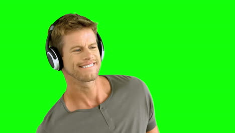 Attractive-man-with-headphones-listening-to-music-on-green-screen