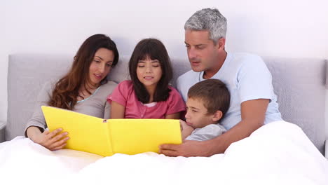 Familia-Leyendo-Un-Cuento-En-La-Cama