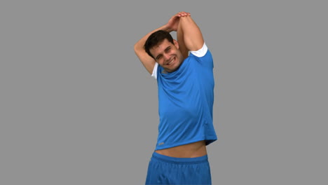 Football-player-stretching-arms-on-grey-screen