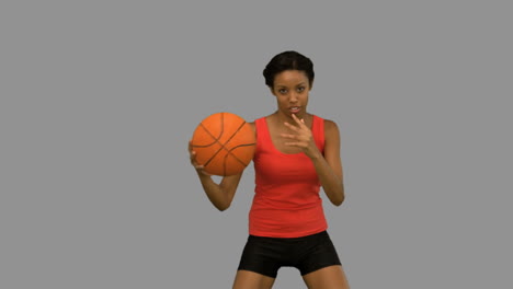 Pretty-woman-playing-basketball-on-grey-screen