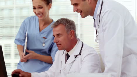 Smiling-medical-team-looking-at-computer-