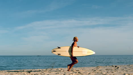 Mujer-Corriendo-En-La-Playa-Con-Su-Tabla-De-Surf