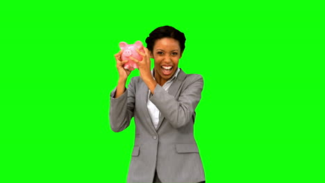 Businesswoman-listening-to-a-full-piggy-bank-on-green-screen