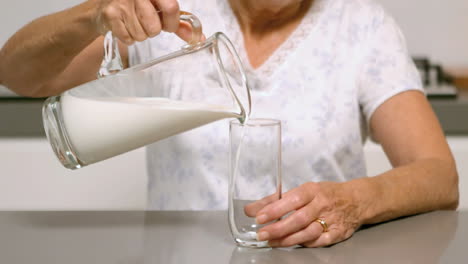 Mujer-Vertiendo-Un-Vaso-De-Leche-En-La-Cocina