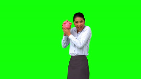 Businesswoman-shaking-a-full-piggy-bank-on-green-screen